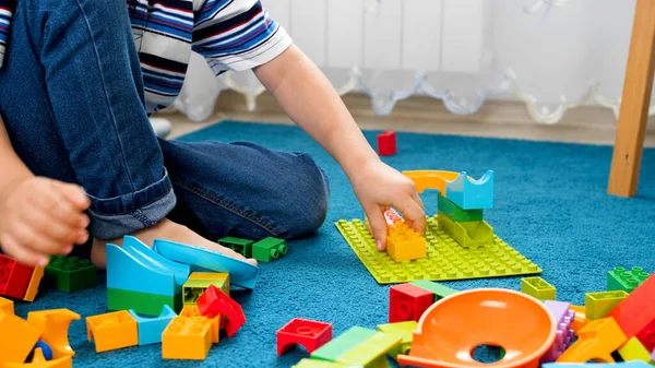 Närbild av liten pojke montera färgglada leksak konstruktör på mattan — Stockfoto