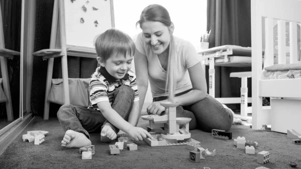 Glad liten pojke med mamma bygga leksak spår med block och tegel — Stockfoto