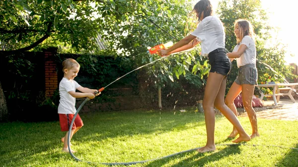 Glada skrattande barn som har vatten pistol slåss på varm solig sommardag — Stockfoto