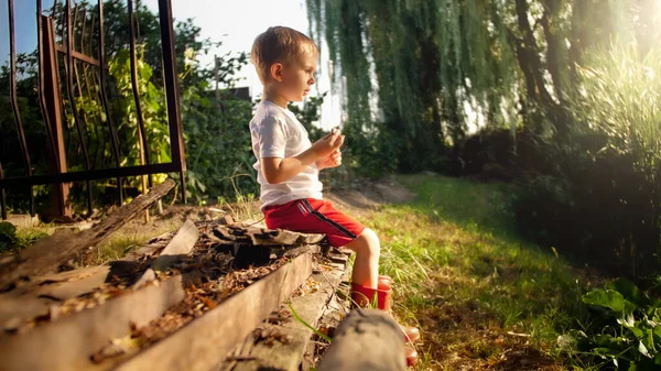 Küçük çocuk nehirde oturuyor ve gün batımını seyrediyor — Stok fotoğraf