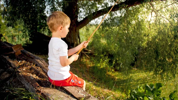 Ritratto di simpatico bambino che cattura il pesce al vecchio stagno in campagna — Foto Stock