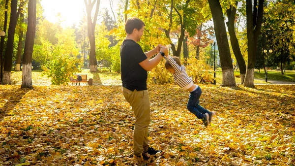 Fiatalember játszik és szórakozik a kisfiával az őszi parkban. — Stock Fotó