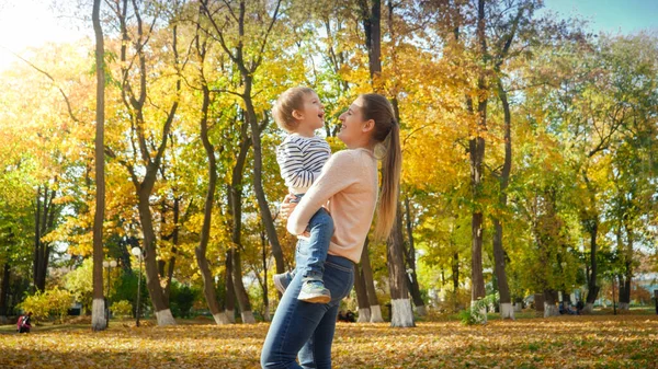 Portret szczęśliwego chłopca uśmiechającego się i obejmującego matkę w jesiennym parku — Zdjęcie stockowe