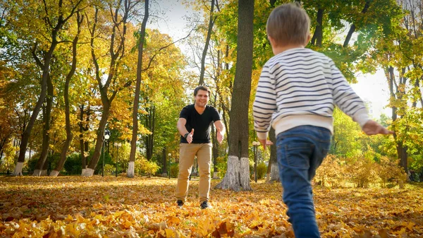 Милий маленький хлопчик біжить до батька в осінньому парку — стокове фото