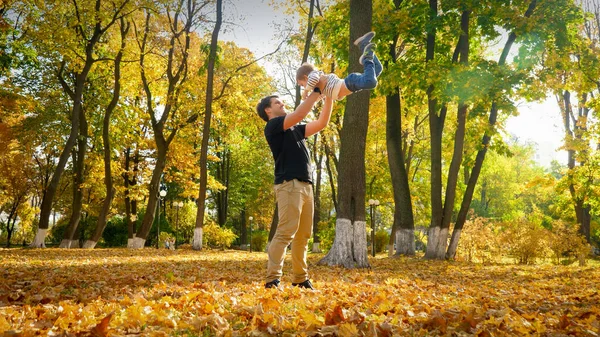 笑着快乐的父亲和他的小儿子在秋天的公园玩耍 — 图库照片
