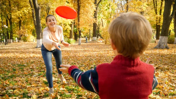 Cute little boy playing in frisbee with his mother at autumn park — Stock Photo, Image