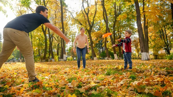 Mutlu gülümseyen aile sonbahar parkında frizbi oynuyor. — Stok fotoğraf