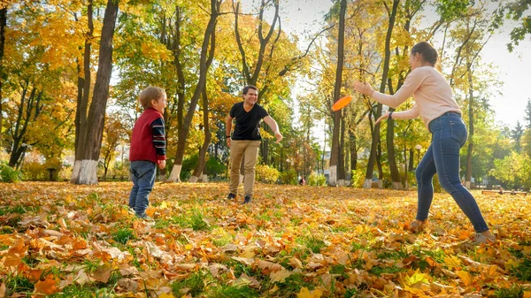 Happy young parents playing with their little son in frisbee at autumn park — Stock Photo, Image