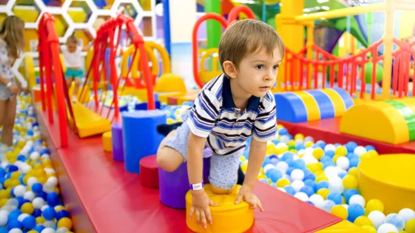 Menino bonito rastejando e jogando no playground colorido no shopping — Fotografia de Stock