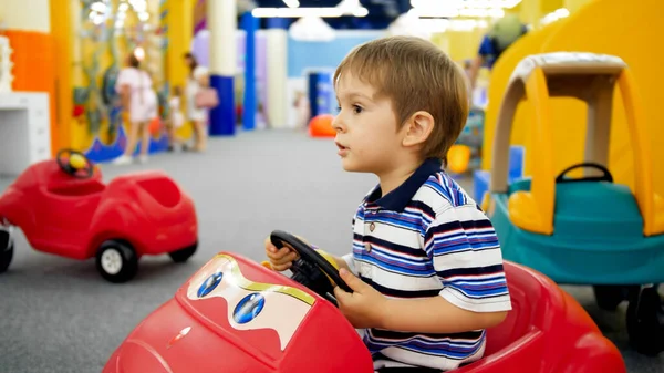 Porträtt av söt liten pojke rider i leksaksbil på köpcentret — Stockfoto