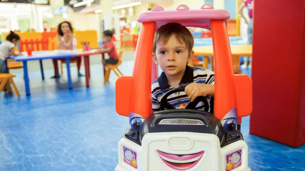 Ritratto di bambino che cavalca nel carrello della spesa giocattolo per bambini nel centro commerciale — Foto Stock