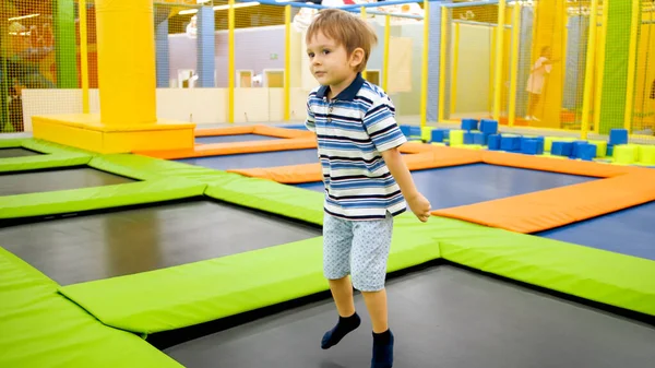Retrato de menino sorridente feliz pulando em trampolins na sala de jogos no shopping — Fotografia de Stock