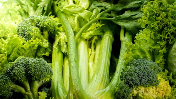 Foto in primo piano di sedano fresco sdraiato su foglie di lattuga verde e broccoli in insalata. Contesto per alimenti sani e prodotti senza OGM. Nutrizione alimentare e verdure fresche. Vegano e vegetariano — Foto Stock
