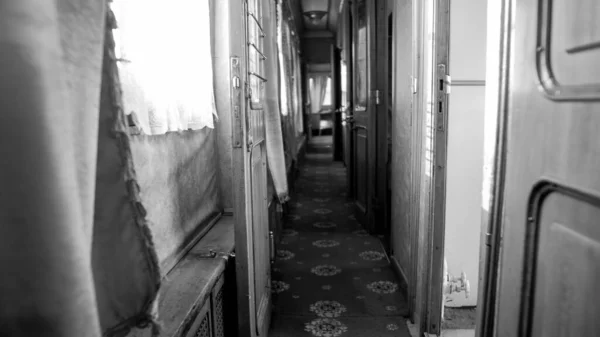 Black and white image of long narrow corridor in vintage train car — Stock Photo, Image