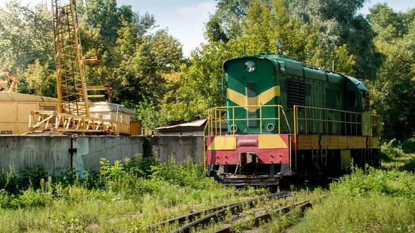 오래 된 디젤 기관차를 타고 오래 된 공장이나 공사장에서 철도를 타는 모습 — 스톡 사진