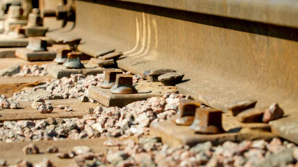 Крупный план старых ржавых гаек и болтов, соединяющих рельсы с деревянными шпал на железной дороге — стоковое фото
