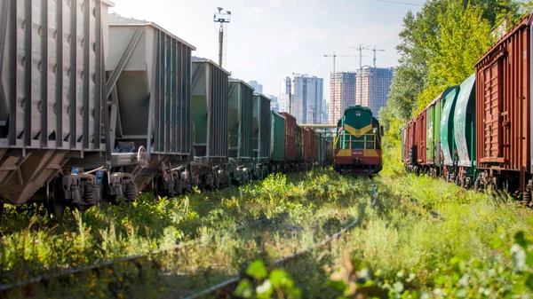 Vecchio treno diesel che viaggia su ferrovia tra file di carri merci e automobili — Foto Stock