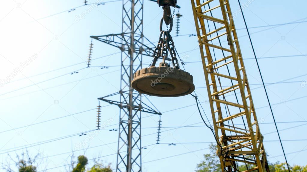 Image of big electric magnet hanging on crane on the dump