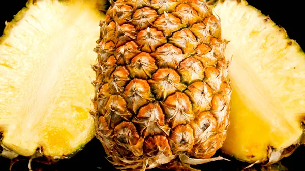 Szoros kép friss vágott ananász vágott felére fekete háttér. Az egzotikus gyümölcsök elvont háttere. — Stock Fotó