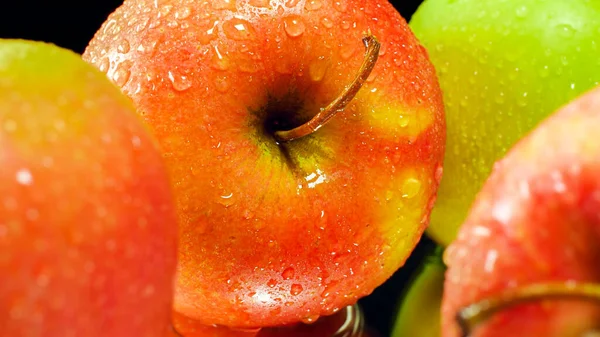 Imagen macro de manzanas húmedas maduras rojas y verdes sobre fondo negro. Fondo abstracto de frutas de temporada — Foto de Stock