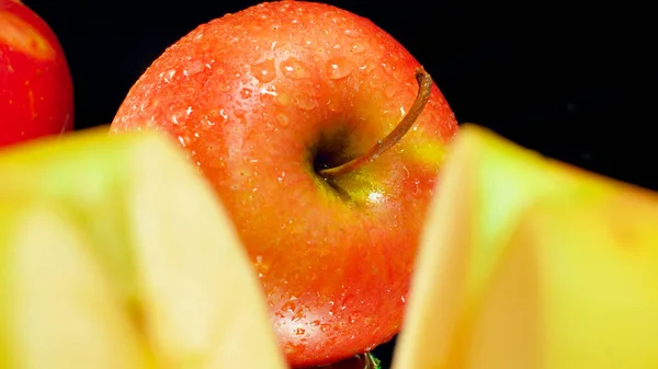 Nahaufnahme von ganzen roten Apfel- und Apfelstücken vor schwarzem Hintergrund. Abstrakter Hintergrund saisonaler Früchte — Stockfoto