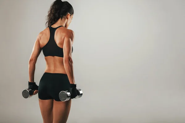 Back of athletic woman holding weights — Stock Photo, Image