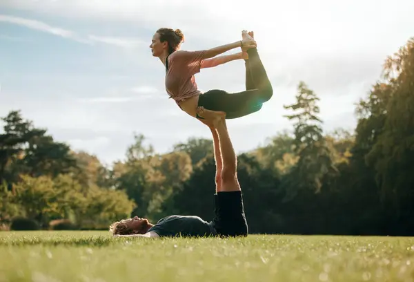 Мужчина лежит и балансирует женщина в его ногах — стоковое фото