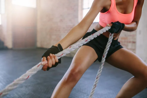 Strong young woman pulling rope at a gym — Stock Photo, Image