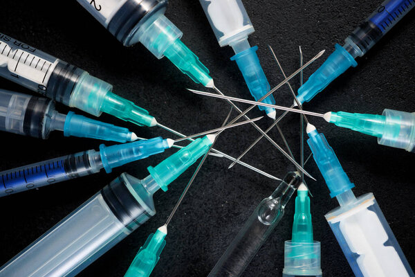 Крупный план группы шприцов на черном столе
.