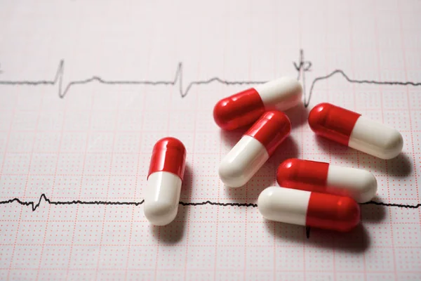 Close up of pills and an electrocardiogram in paper form.