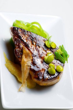 Beyaz tabakta sebzeli kaz ciğeri.