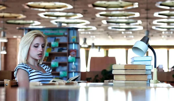 Colegiala o estudiante lee en voz alta el libro sentado en una mesa —  Fotos de Stock