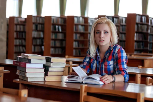 Jong blond meisje in een plaid shirt zitten aan tafel — Stockfoto