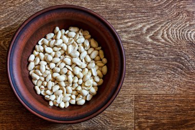 Ahşap bir masa üzerinde bir tabak içinde soyulmuş fıstık