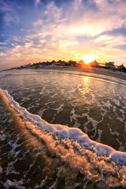 Panoramik günbatımı deniz, kum plaj, dalgalar ve balık gözü lens thatched şemsiye