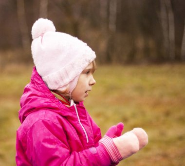 Bir kırmızı ceket ve beyaz şapka eldiven ellerini alkışlar sokakta oynuyor. Sonbahar.