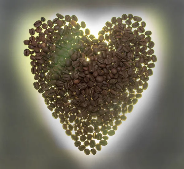Coração de grãos de café. Iluminado de baixo, ou sem iluminação, um fundo de madeira — Fotografia de Stock