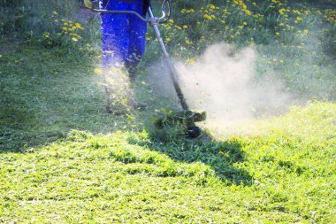 Mavi elbiseli bir adam. Koruyucu bir kask ve kulaklık. Otlar hasat üretir. Yüz odaklanmak değil