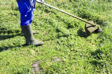 Mavi elbiseli bir adam. Koruyucu bir kask ve kulaklık. Otlar hasat üretir. Yüz odaklanmak değil