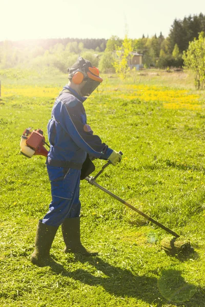 Ein Mann im blauen Anzug. mit Schutzhelm und Kopfhörer. produziert Kräuter ernten. das Gesicht nicht fokussiert — Stockfoto