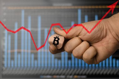 Bir adam elinde bir bitcoin para tutar ve onu büker. Bitcoin büyüme grafiği.