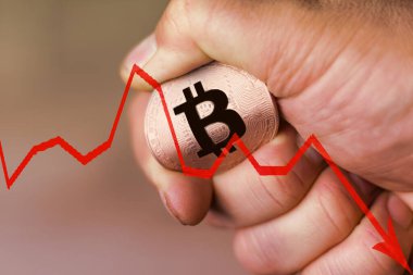 Bir adam elinde bir bitcoin para tutar ve onu büker. konsept onun üzerindeki baskıya dayanamaz ve düşer..