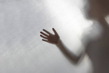 Odaklanma. Arkasındaki kumaş. Siluet ve gölge. Eli kumaşa değmiş çocuk, lütfen yardım et. aile içi şiddet kavramı.