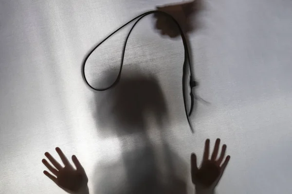 No focus. the fabric behind her. silhouette and shadow. child over head strap. domestic violence concept. — Stock Photo, Image