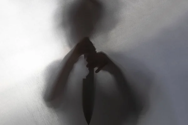 No focus. the fabric behind her. silhouette and shadow. the child has a knife in his hands. domestic violence concept. — ストック写真