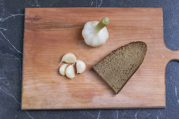 Ail trempé dans une sauce spéciale. à côté d'un morceau de pain de seigle noir. Gros plan. sur un fond en bois . — Photo