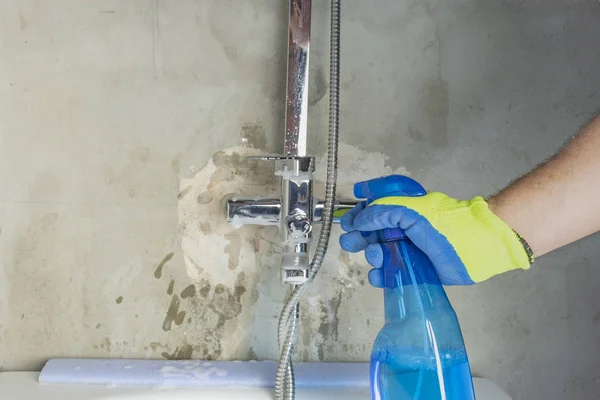 En man i gula handskar tvättar en kran i badrummet, tillämpar speciella rengöringsmedel. närbild. — Stockfoto