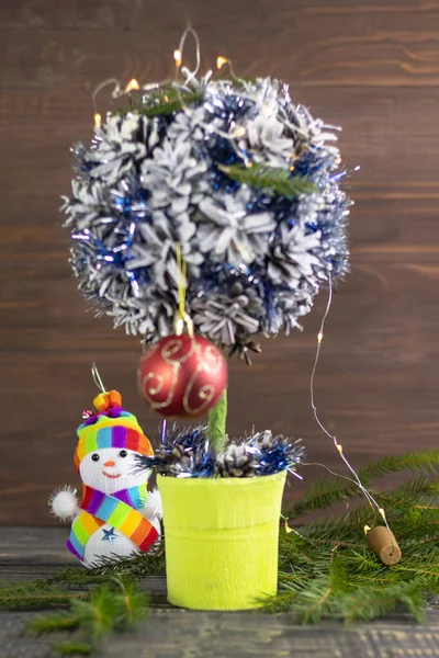 Creative tree of small stature. garland included. the snowman is out of focus — Stock Photo, Image