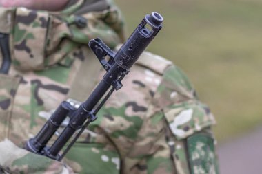 Yakın plan, Kalaşnikov saldırı tüfeği, bir askerin göğsünde. Rengi var.