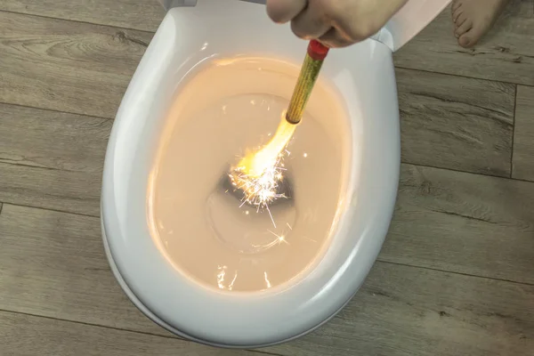 Castron de toaletă alb pe un fundal din lemn. Mâna coboară focul aprins. Închidere . — Fotografie, imagine de stoc